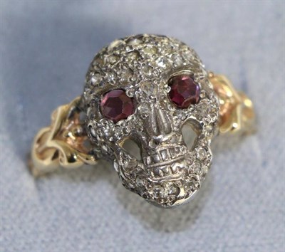 Lot 648 - A ruby and diamond skull ring, pavé set with rose cut diamonds and with rose cut ruby eyes, to...