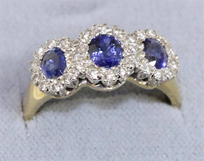 Lot 680 - An 18 carat gold sapphire and diamond triple cluster ring, oval cut sapphires within borders of...