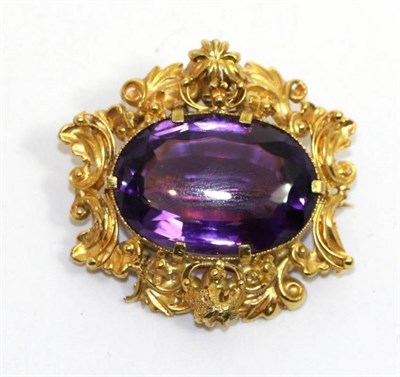 Lot 685 - An amethyst brooch, an oval cut amethyst in a claw setting and within a pierced foliate scroll...