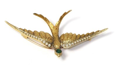 Lot 701 - An emerald and seed pearl set swallow brooch, with textured feathers and a round cut emerald to the