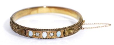 Lot 709 - An opal and diamond bangle, the front with three oval opals spaced by two old cut diamonds in...