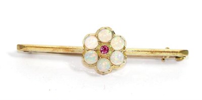 Lot 710 - An opal and ruby bar brooch, a round cut ruby within a border of round cut opals in collet...