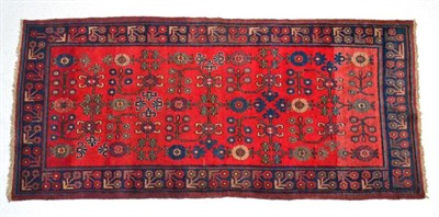 Lot 1357 - East Turkestan rug, Khotan, the abrashed crimson field of angular vines enclosed by indigo...