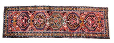 Lot 1362 - Heriz runner, Iranian Azerbaijan, the brick red field with five polychrome medallions enclosed...