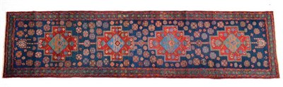 Lot 1375 - Narrow Heriz runner, Iranian Azerbaijan, the indigo field with four madder stepped medallions...