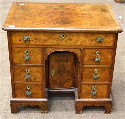 Lot 1410 - A George II walnut kneehole desk, early 18th century, the feather banded top with reentrant corners