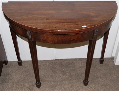 Lot 1422 - ^ A George III mahogany demi-lune fold over tea table, circa 1780, the carved patra above...