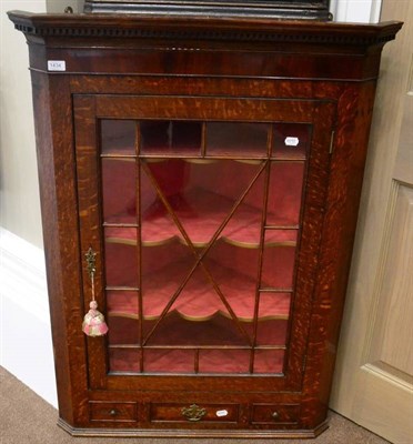 Lot 1434 - A George III oak and mahogany hanging corner cupboard, with dentil cornice above an astragal glazed