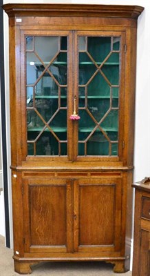 Lot 1436 - A George III oak ebony strung freestanding corner cupboard, circa 1800, with astragal glazed...