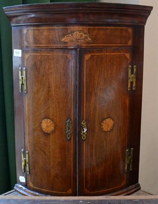 Lot 1490 - ^ An 18th century mahogany bow fronted marquetry hanging corner cupboard, two doors inlaid with...