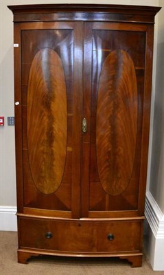 Lot 1495 - ^ An Edwardian mahogany and ebony strung bow fronted wardrobe, with two doors enclosing hanging...