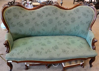 Lot 1536 - A Victorian carved mahogany two-seater sofa, upholstered in green floral moquette, with a...