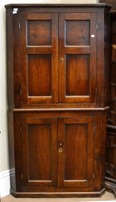 Lot 1637 - A George III oak freestanding corner cupboard, the upper section with four fielded panel...