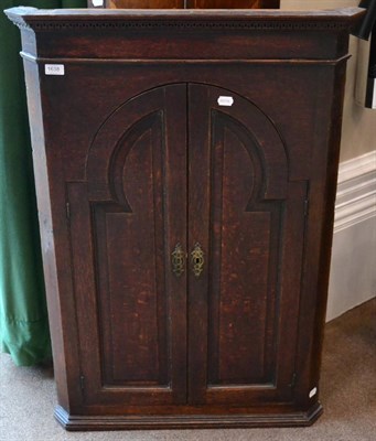 Lot 1638 - A George III oak hanging corner cupboard, with Greek key cornice above moulded cupboard doors...