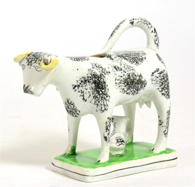 Lot 196 - A Pearlware Cow Creamer, 19th century, the standing beast with black sponged markings, a calf...