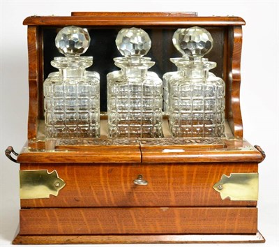 Lot 490 - A Victorian Oak Three Bottle Tantalus, circa 1890, the base with hinged cover enclosing...