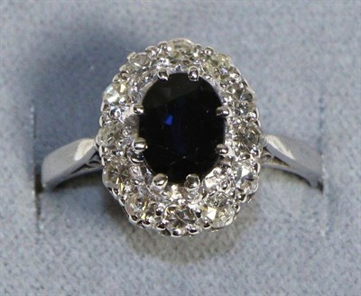 Lot 596 - A Sapphire and Diamond Cluster Ring, an oval cut sapphire within a border of eight-cut diamonds...