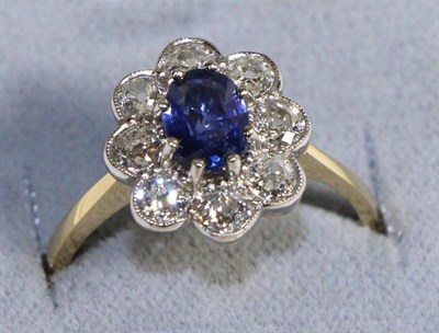 Lot 603 - A Sapphire and Diamond Cluster Ring, an oval cut sapphire in a claw setting within a border of...