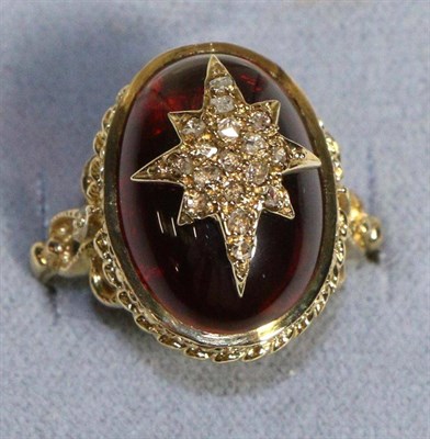 Lot 611 - A 9 Carat Gold Carbuncle Garnet and Diamond Ring, an oval garnet inset with a diamond set star...