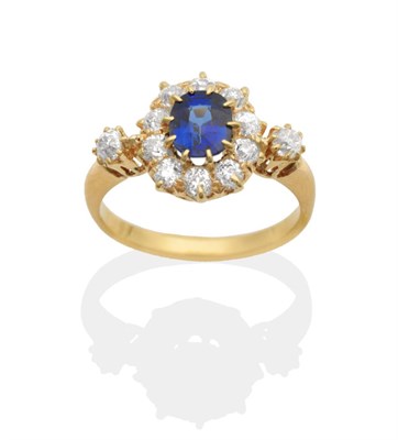 Lot 626 - A Sapphire and Diamond Cluster Ring, an oval cut sapphire in a claw setting within a border of...