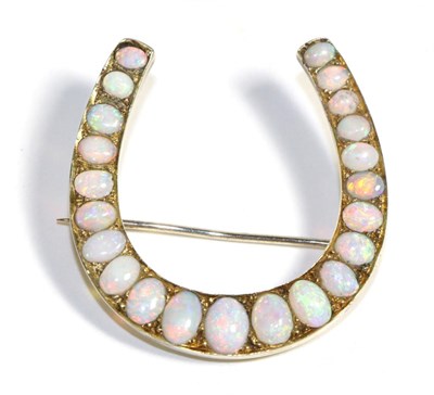 Lot 646 - An Opal Horseshoe Brooch, set with graduated oval cabochon opals, in claw settings, measures...