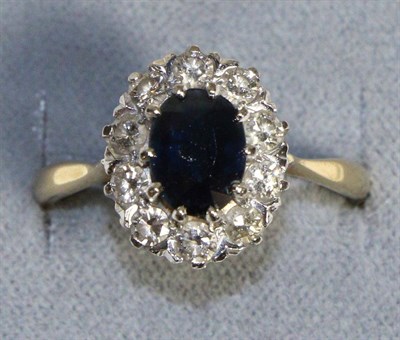 Lot 672 - An 18 Carat Gold Sapphire and Diamond Cluster Ring, an oval cut sapphire in a claw setting,...