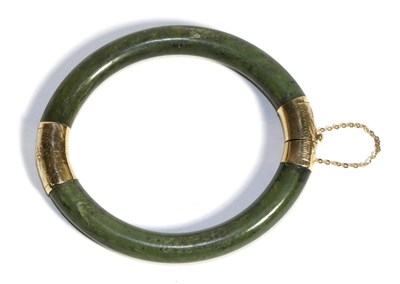 Lot 715 - A Nephrite Bangle, a hinge opening bangle with foliate engraved mounts, measures 6cm by 5cm...