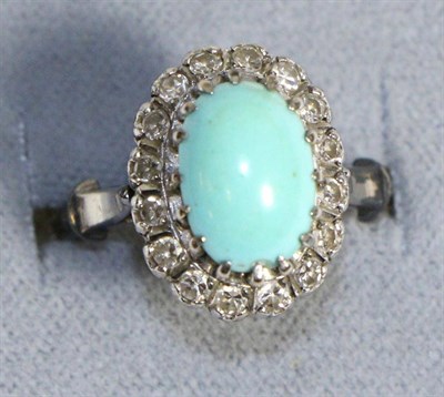 Lot 722 - A Turquoise and Diamond Cluster Ring, an oval cabochon turquoise in a claw setting, within a border