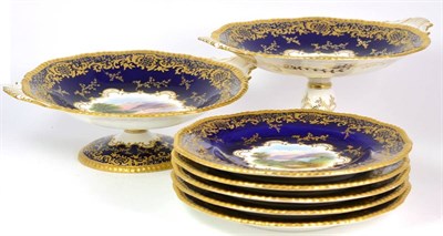 Lot 103 - A Coalport Porcelain Named Views Dessert Service, circa 1910, painted with landscapes on a blue and