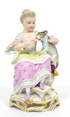 Lot 121 - A Meissen Porcelain Figure of a Girl, circa 1900, sitting on a stool feeding a cat from a bowl,...