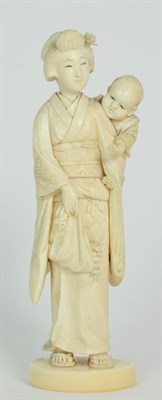 Lot 244 - A Japanese Ivory Okimono, Meiji period, as a mother holding her boy over her shoulder, on an...