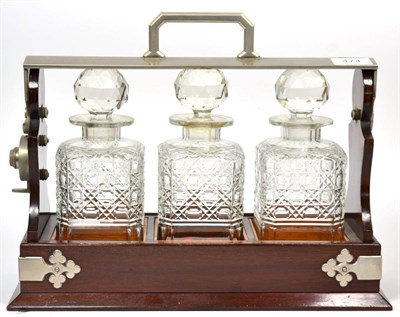 Lot 474 - A Steel Mounted Mahogany Three Bottle Tantalus, circa 1900, with hobnail cut spirit decanters...