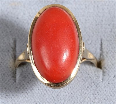 Lot 631 - A Coral Ring, an oval cabochon coral in a rubbed over setting, to forked shoulders, finger size Q