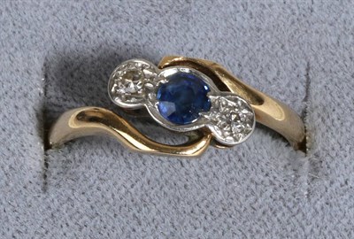 Lot 657 - A Sapphire and Diamond Three Stone Ring, a round cut sapphire in a rubbed over setting between...