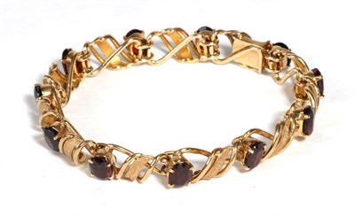 Lot 680 - A 9 Carat Gold Garnet Bracelet, by Deakin & Francis, oval cut garnets in claw settings, spaced...