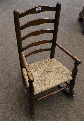 Lot 1396 - A 19th Century Child's Ash and Rush Seated Ladder-Back Rocking Armchair, with spindle arm supports