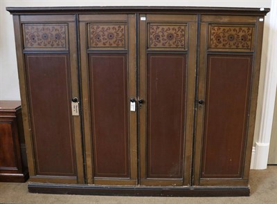 Lot 1446 - An Arts & Crafts Brown Painted Four Door Wardrobe, with moulded cornice above four panelled...