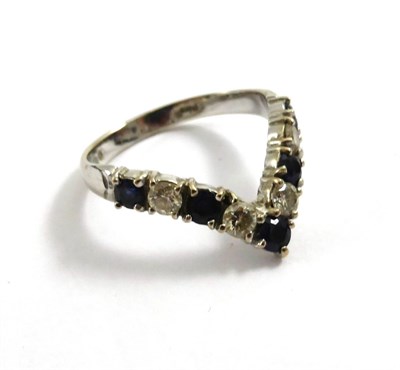 Lot 2149 - An 18ct White Gold Sapphire and Diamond Wishbone Ring, 1975, five round cut sapphires alternate...