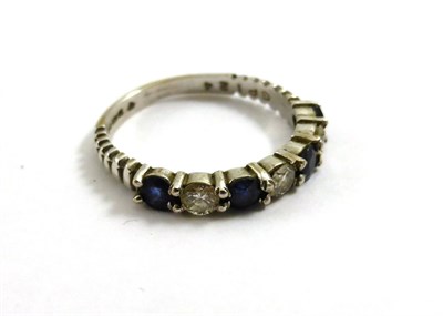 Lot 2159 - An 18ct White Gold Sapphire and Diamond Half Eternity Ring, 1975, four round cut sapphires...