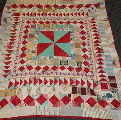 Lot 2056 - A 19th Century Geometric Patchwork Quilt, with red floral trim and white reverse, 225cm by 295cm