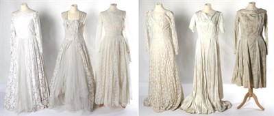 Lot 2135 - Circa 1940s to 1960s Wedding Dresses, comprising an ivory silk brocade long sleeved midi length...