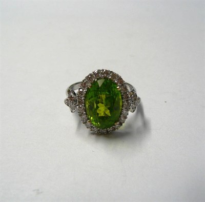 Lot 111 - An 18 Carat White Gold Peridot and Diamond Cluster Ring, an oval cut peridot within a border of...