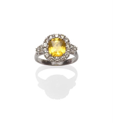 Lot 128 - An 18 Carat White Gold Yellow Sapphire and Diamond Cluster Ring, the central cushion shaped...