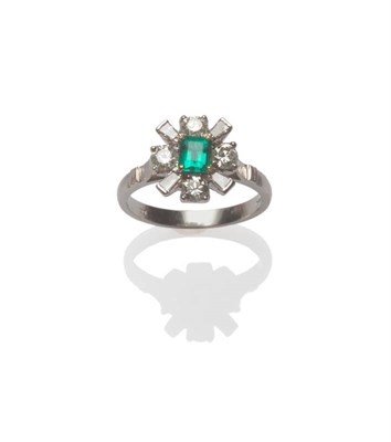 Lot 134 - An 18 Carat White Gold Emerald and Diamond Cluster Ring, the step cut emerald centrally within...