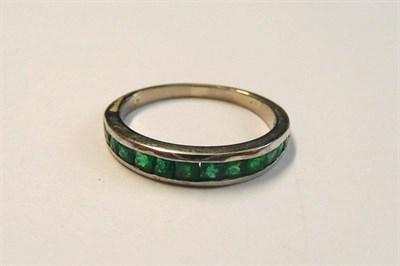 Lot 138 - An Emerald Half Eternity Ring, the graduated faceted emeralds in a white channel setting to a plain