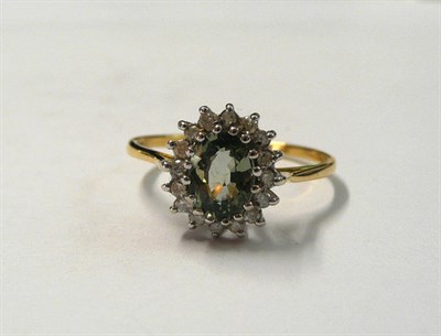 Lot 167 - An 18 Carat Gold Green Sapphire and Diamond Cluster Ring, the oval mixed cut green sapphire...