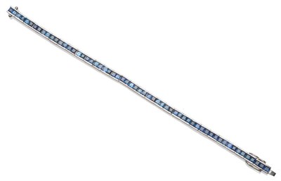 Lot 185 - An 18 Carat White Gold Sapphire Line Bracelet, the step cut sapphires in articulated white claw...