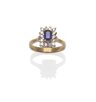 Lot 187 - A 9 Carat Gold Sapphire and Diamond Oblong Cluster Ring, a step cut sapphire within a border of...