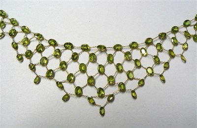 Lot 204 - A Bib Necklace, of oval cut peridots bezel set, and chain linked to form a V shape, length 41.5cm