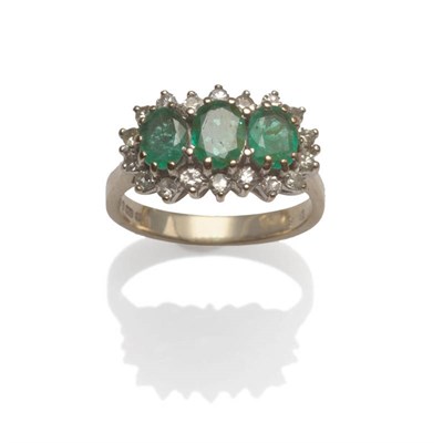 Lot 26 - An 18 Carat White Gold Emerald and Diamond Triple Cluster Ring, the oval cut emeralds within a...